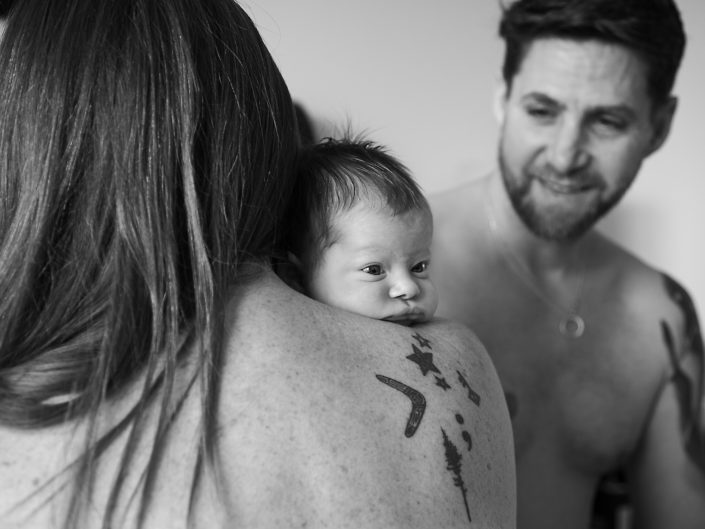 A couple cradles their newborn in a cozy room, enveloping the infant in love and warmth.