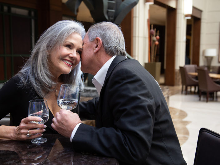 Elderly couple sharing a kiss at a restaurant.
