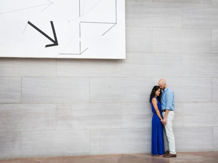 Two people posing in front of a massive wall.