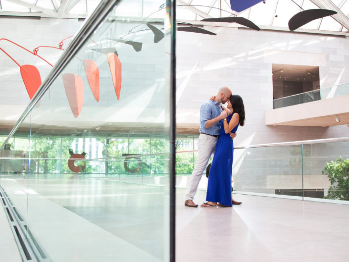 Couple embracing in a sleek glass building, radiating love.