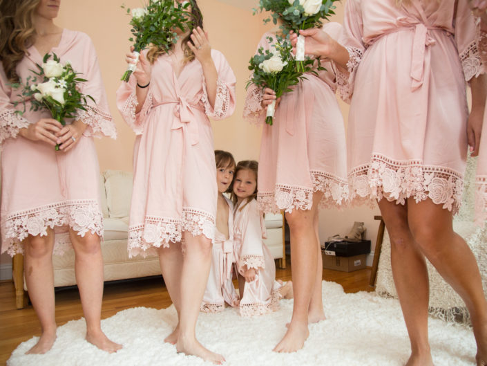 Bridesmaids in pink robes with bride, radiating elegance.
