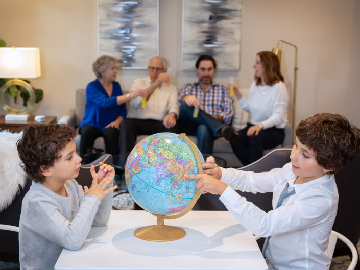 Family of six engrossed around table with globe.