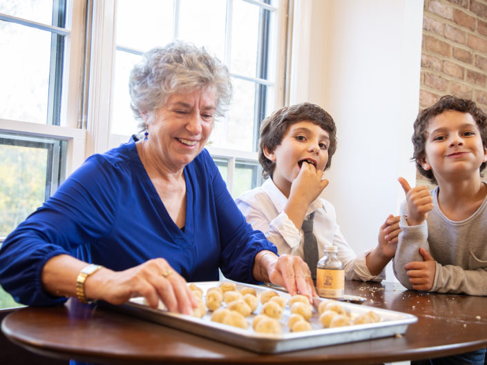 Elderly woman and children enjoying cookies at a table.