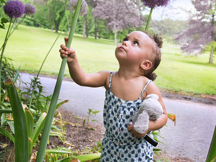 Curious baby captivated by vibrant flower.