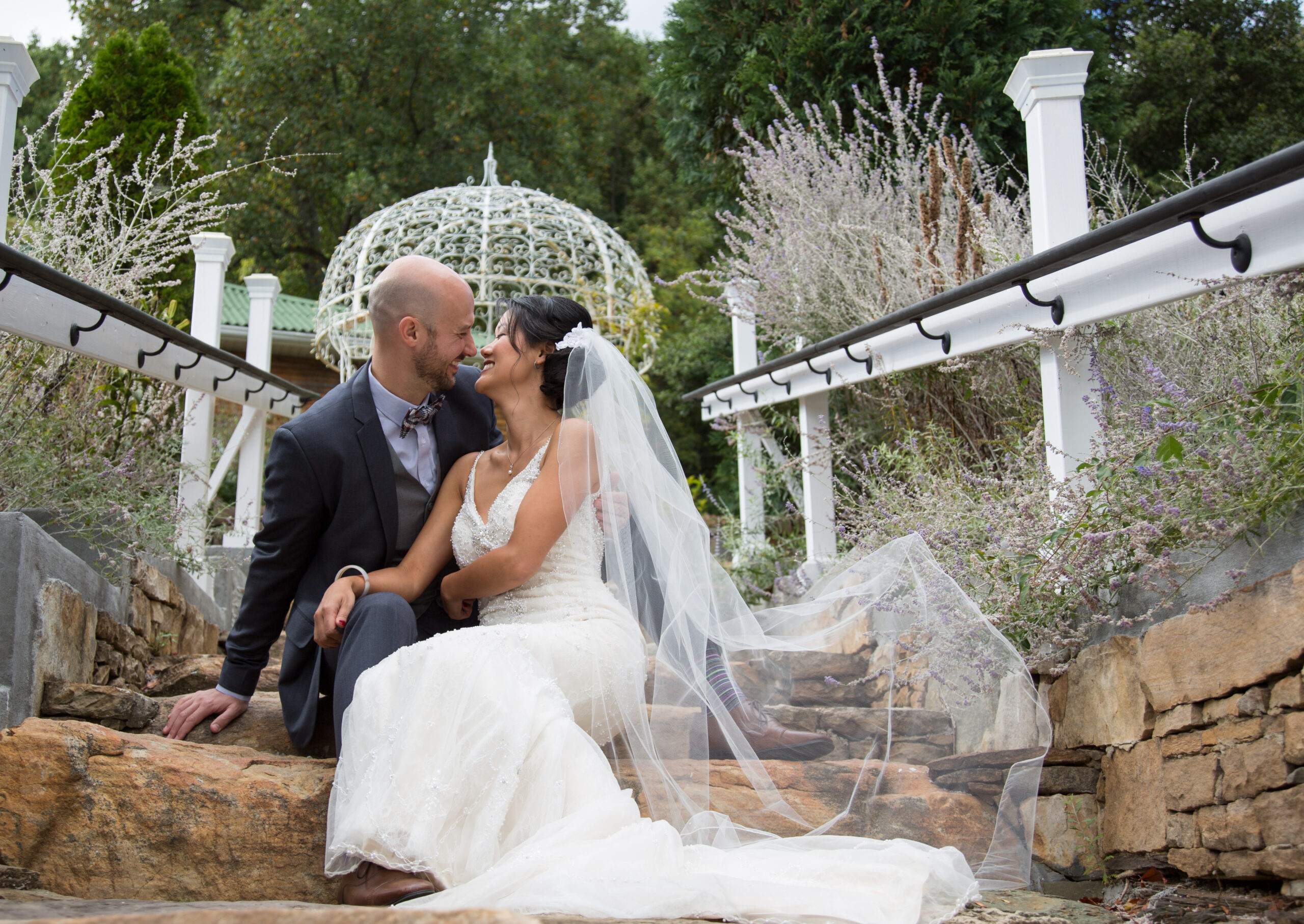 A bride and groom sitting on steps in front of a gazebo