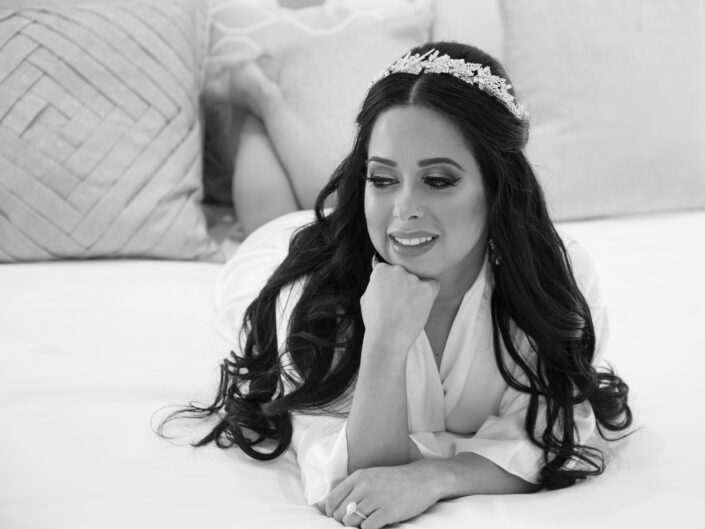 A bride laying on a bed with a tiara on her head.