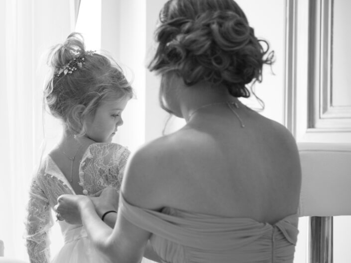 A mother is helping her little girl put on her dress.