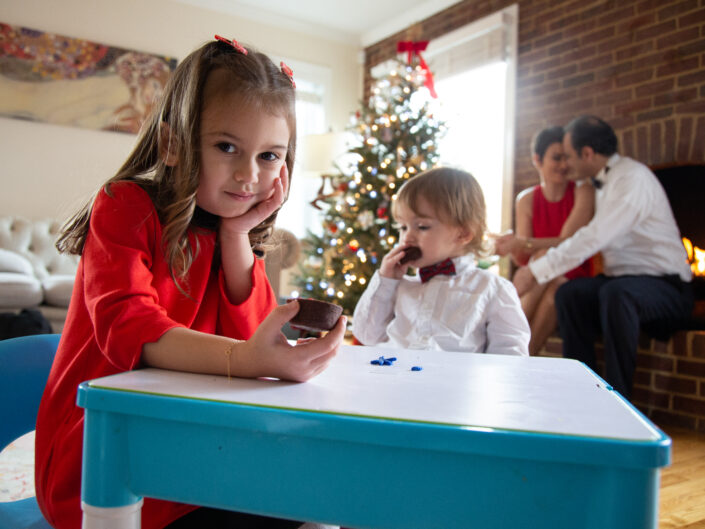 A girl and a boy sitting at a table in front of a christmas tree.