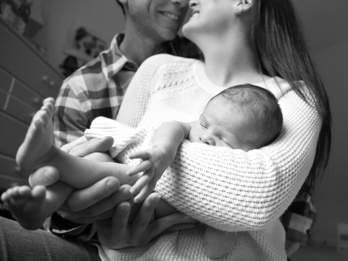 Joyful couple gazing at each other with their newborn baby