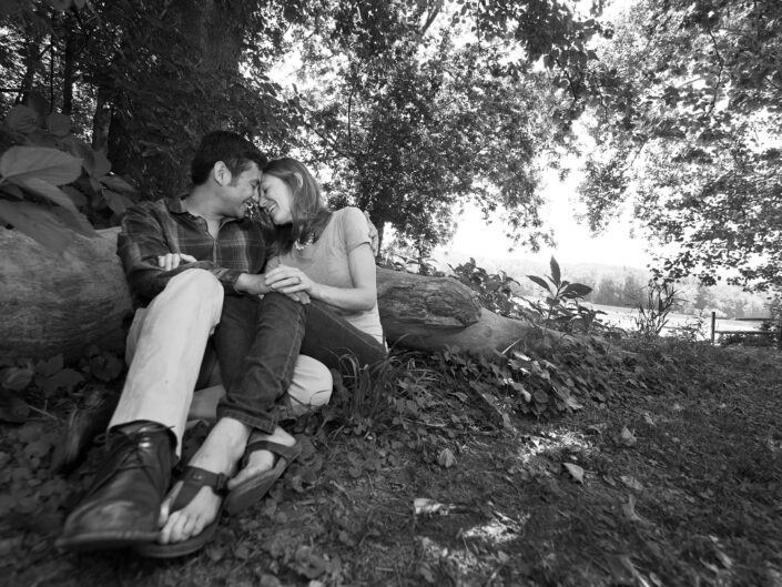 Romantic couple embracing each other while seated on a forest floor, surrounded by woodland