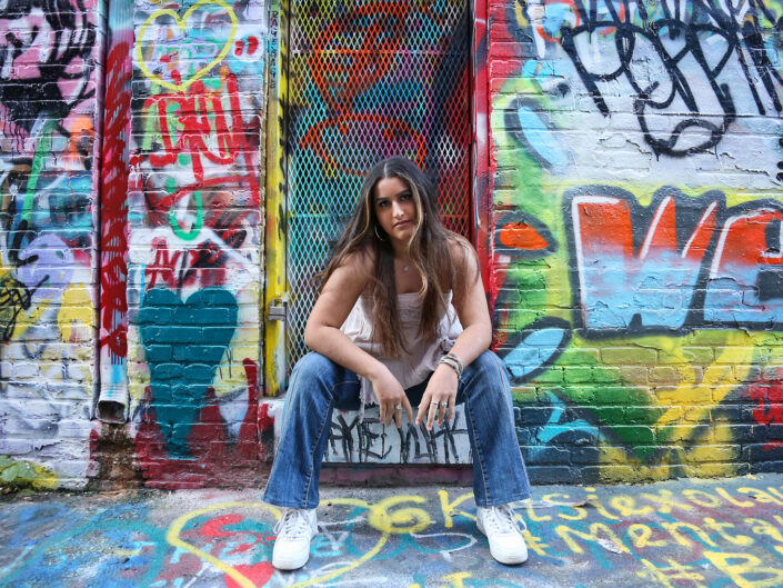 Young woman posing in front of a lively, colorful wall, radiating cheerfulness