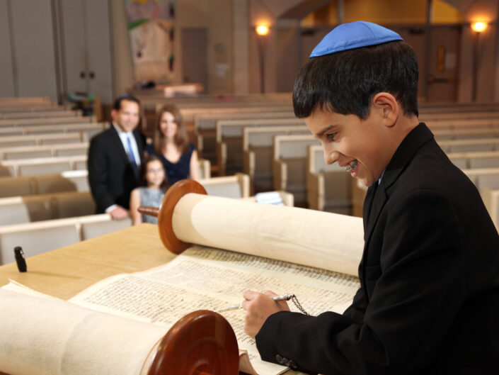 Boy reading the Bible in church with his family watching