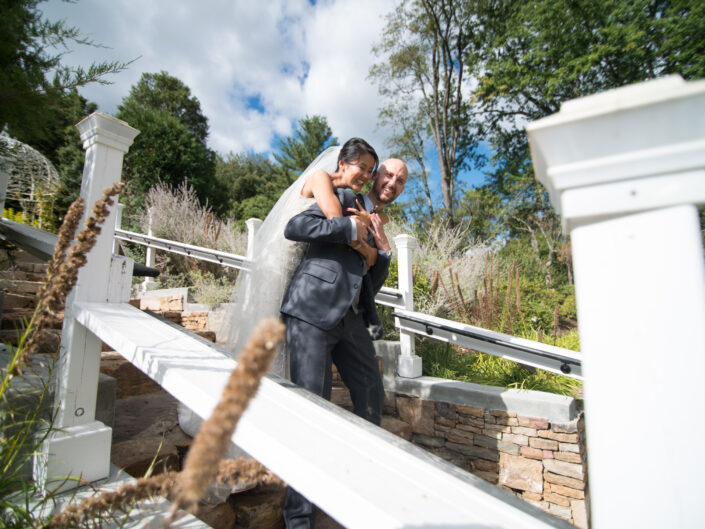 A bride and groom hugging on the steps of a garden.